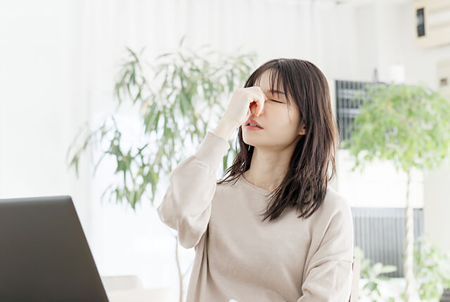 目の疲れで目頭を押さえる女性
